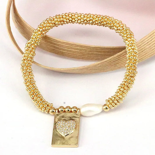 Pulsera dorada de corazon con balines y perla